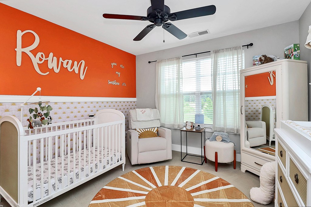 A baby nursery with a white crib and a white chair.