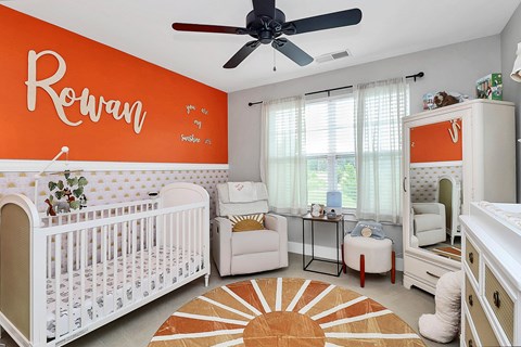 A baby nursery with a white crib and a white chair.
