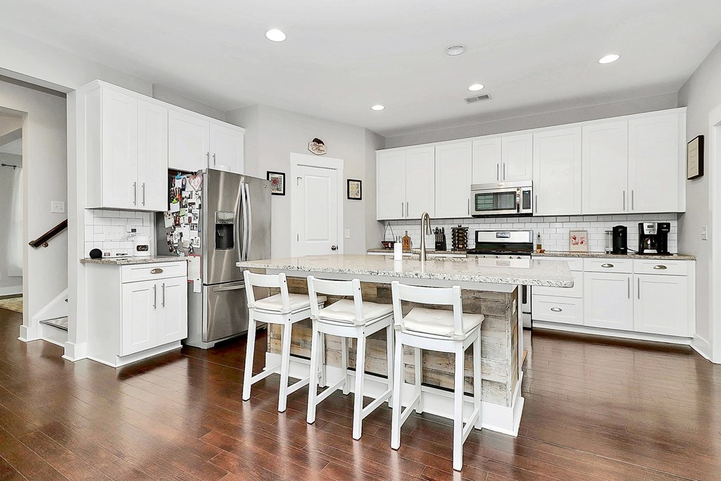 A kitchen with white cabinets and a wooden floor.