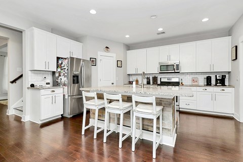 A kitchen with white cabinets and a wooden floor.