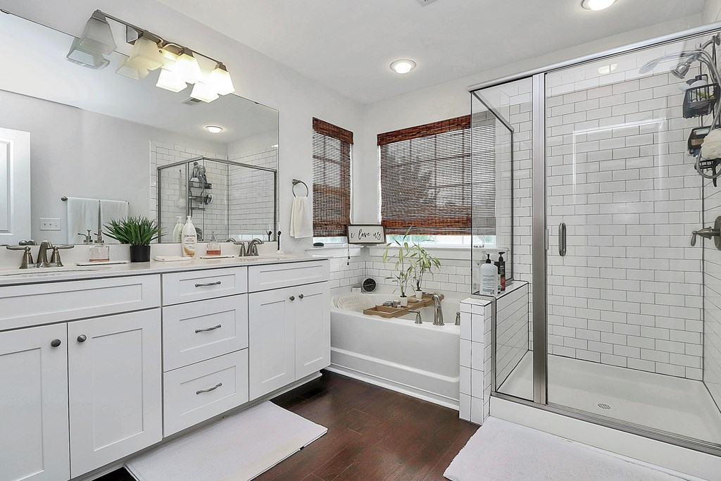 A white bathroom with a large mirror and a bathtub.