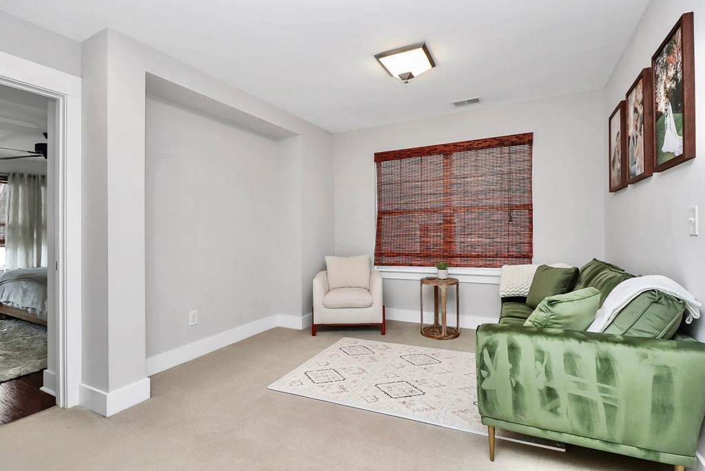 A living room with a green couch and a red window blind.
