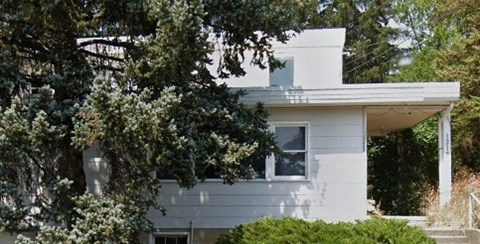 A white house with a tree in front.