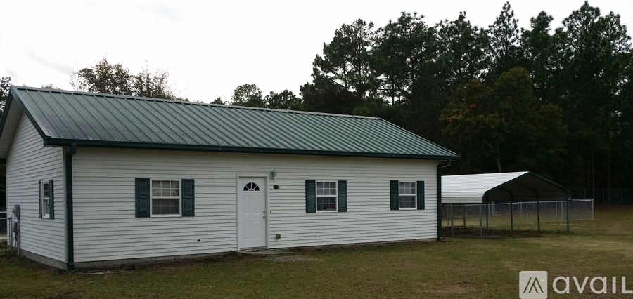 A small white house with a green roof is available for purchase.