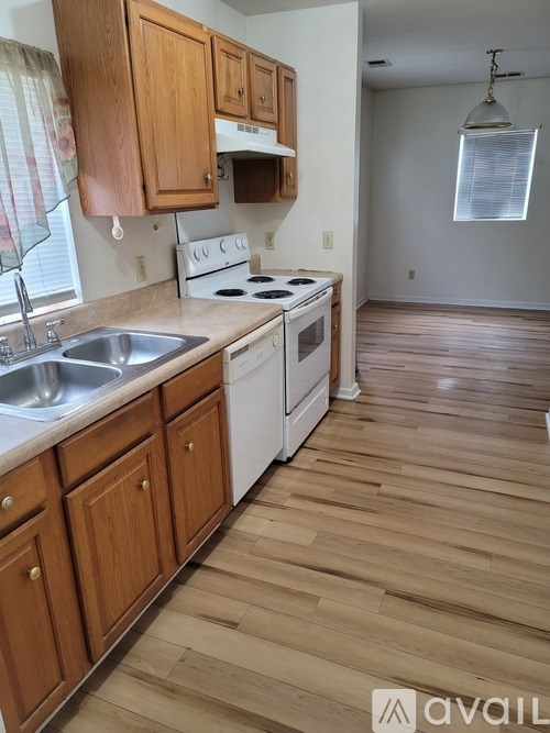 A kitchen with wooden cabinets and a white stove top oven.