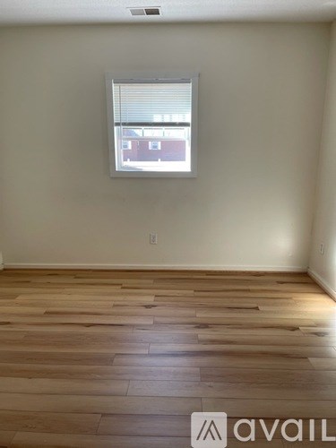 A room with wooden flooring and a window with blinds.