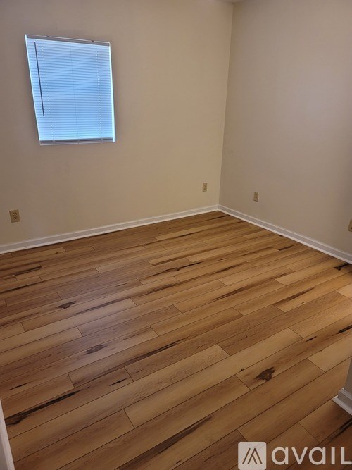 A room with wooden flooring and a window with blinds.