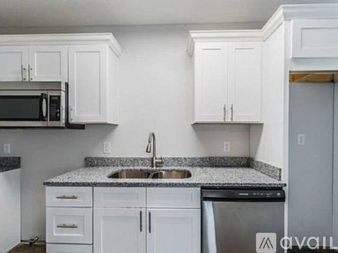 A kitchen with white cabinets and a granite countertop.