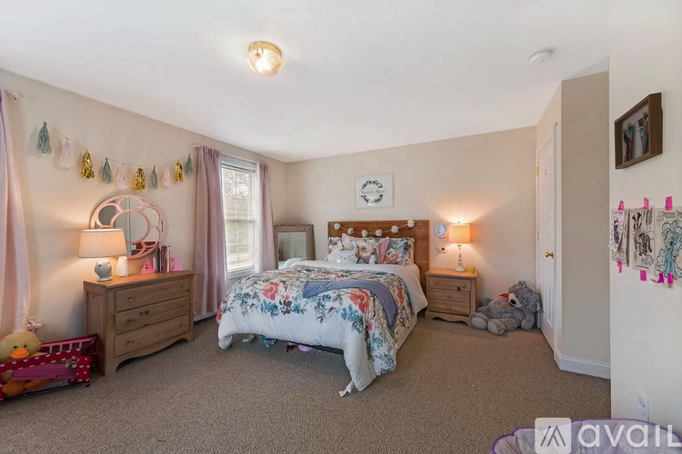 A bedroom with a large bed and a dresser with a lamp on it.