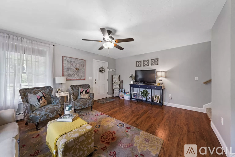 A living room with a yellow ottoman and a television.