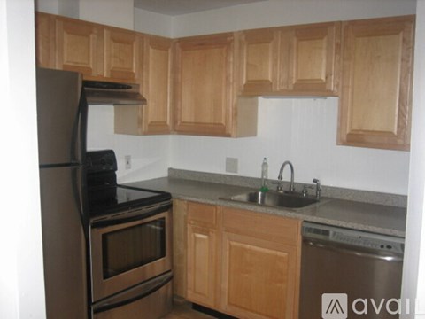 A kitchen with wooden cabinets and a black refrigerator.