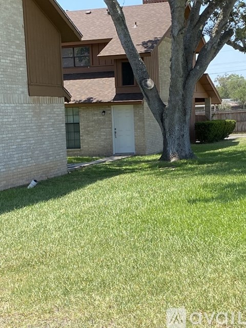 A tree in front of a house with a white door.
