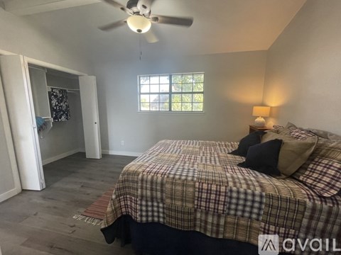 A bedroom with a bed, a ceiling fan, and a window.