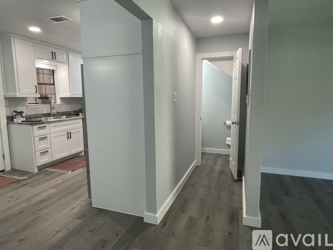 A kitchen with white cabinets and a wooden floor.