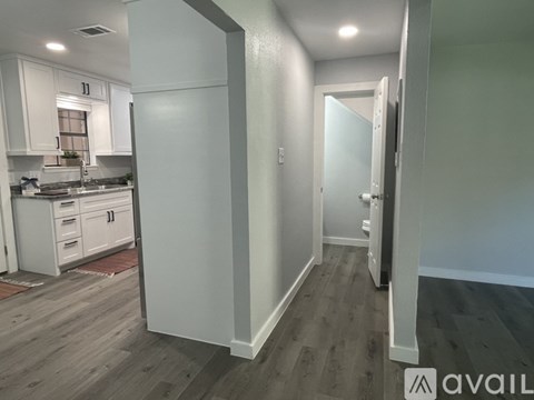 A kitchen with white cabinets and a wooden floor.