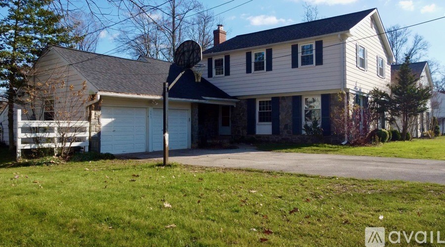 A house with a white exterior and a black roof is for sale.
