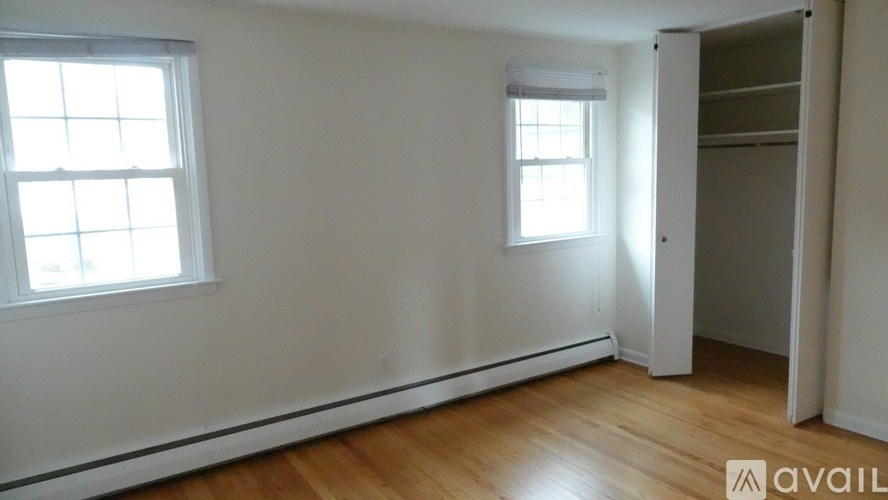 A room with wooden floors and two windows.