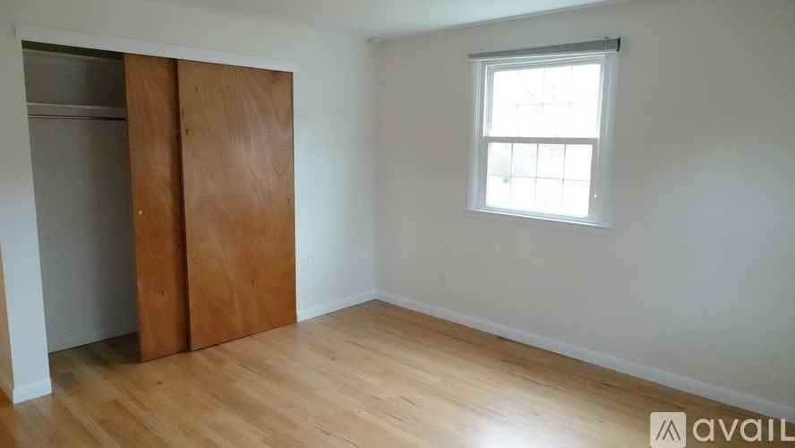 A room with a wooden floor and a window with a white frame.