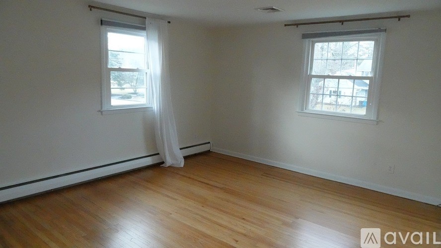 A room with wooden floors and two windows.