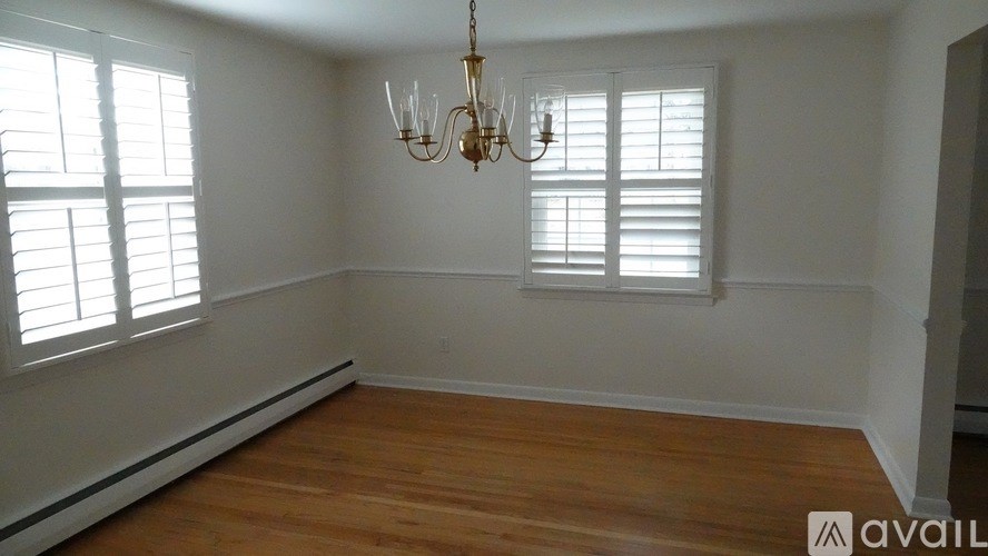 A room with wooden floors and a chandelier hanging from the ceiling.