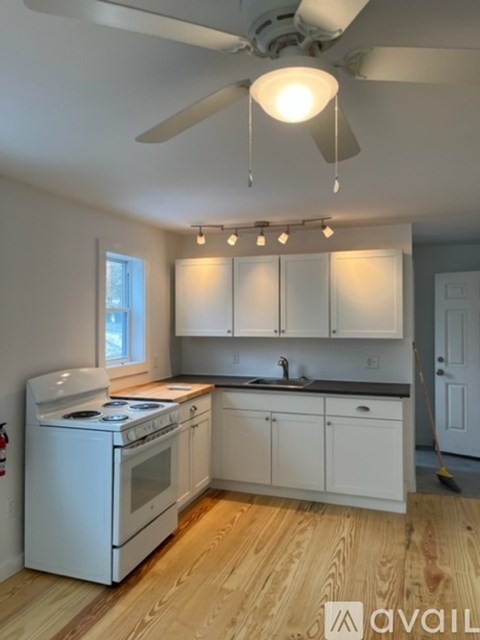 A kitchen with white appliances and wooden floors.
