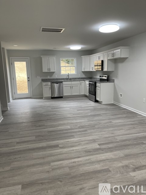 A kitchen with white cabinets and a wooden floor.