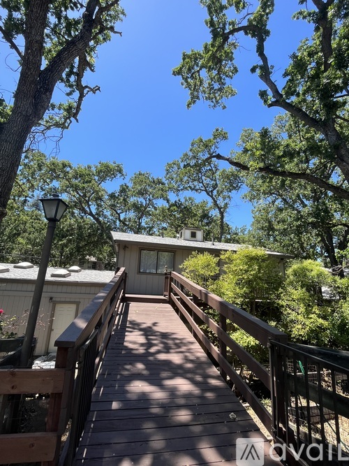 A wooden deck leads to a house with a balcony.
