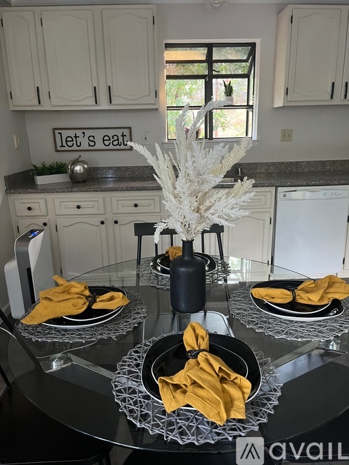 A kitchen with a glass table and a sign that says "let's eat" on the wall.
