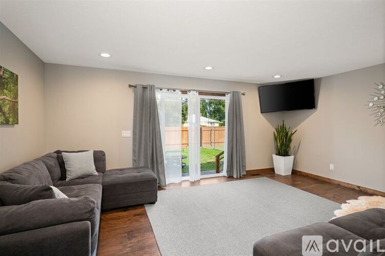 A living room with a grey couch and a flat screen TV mounted on the wall.