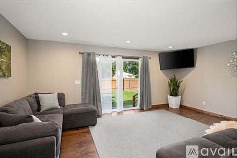 A living room with a grey couch and a flat screen TV mounted on the wall.