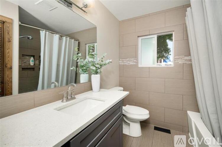 A bathroom with a white sink, toilet, and a window with a view of trees.