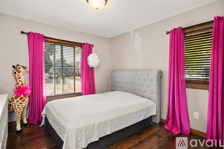A bedroom with a white bed and pink curtains.