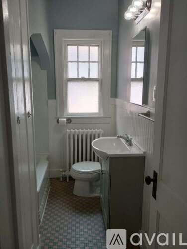 A small bathroom with a toilet, sink, and a window.