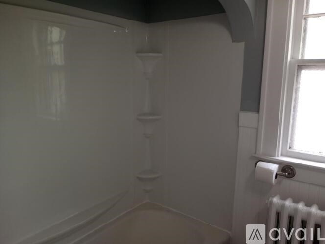 A white bathroom with a toilet paper roll on the wall.