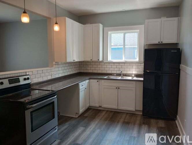 A kitchen with black appliances and white cabinets.
