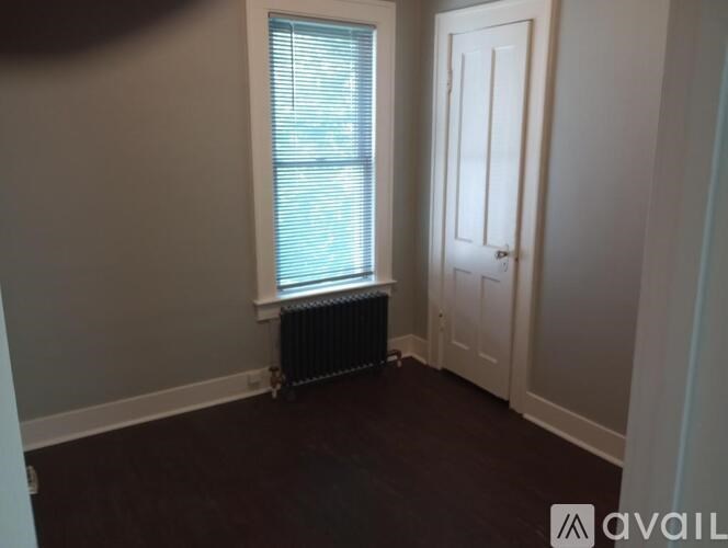 A room with a window, a radiator, and a door.