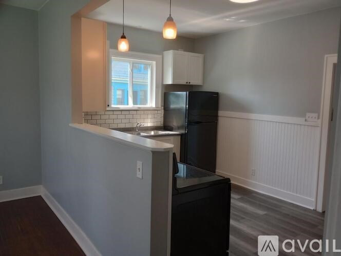 A kitchen with a black fridge and a window with white blinds.