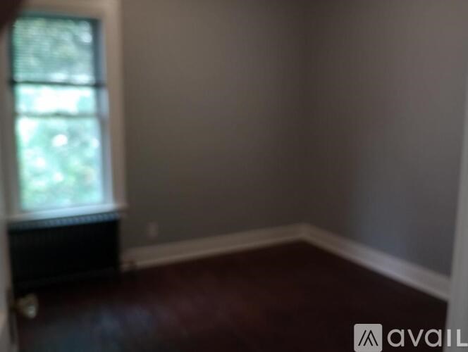 A room with a window and a dark brown floor.