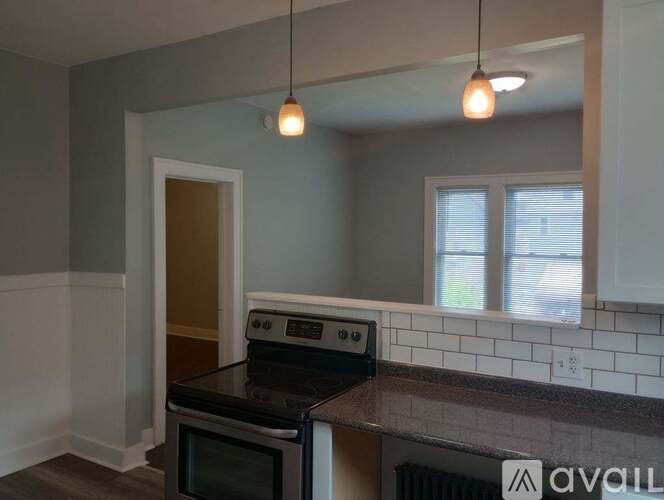 A kitchen with a black stove top oven and a window with blinds.