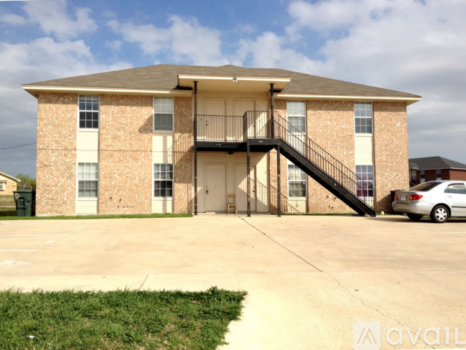 A two-story brick apartment building with a balcony on the second floor.