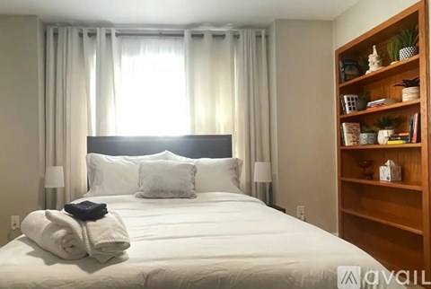 A neatly made bed with white bedding and a black headboard is in the center of the room.