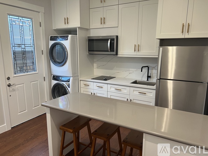 A kitchen with white cabinets and a stainless steel refrigerator.