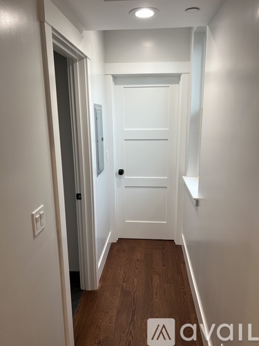 A hallway with a white door and wooden floor.