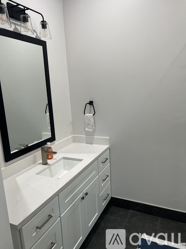 A white bathroom sink with a black mirror above it.