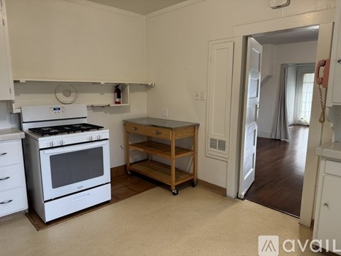 A kitchen with white appliances and a wooden cart.