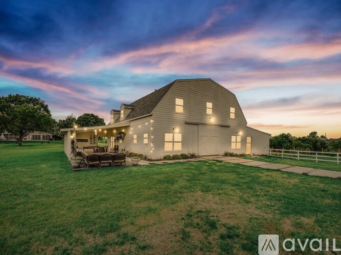A barn with a patio and lights on is available for purchase.