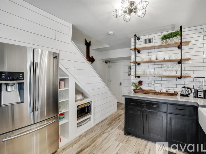 A kitchen with a stainless steel refrigerator and wooden flooring.