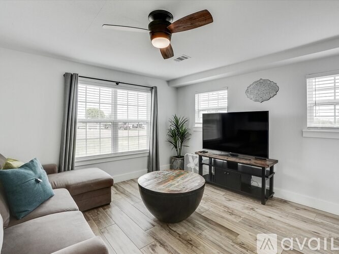 A living room with a television, a couch, and a ceiling fan.