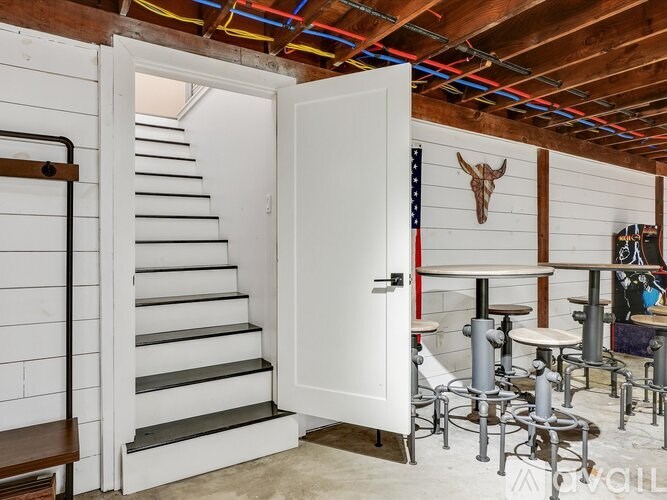 A room with a white door, a staircase, and a wooden wall.