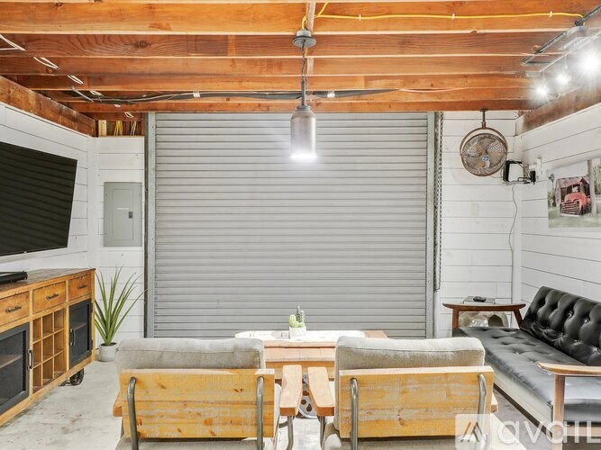A wooden table with a bench in front of a grey roller shutter.